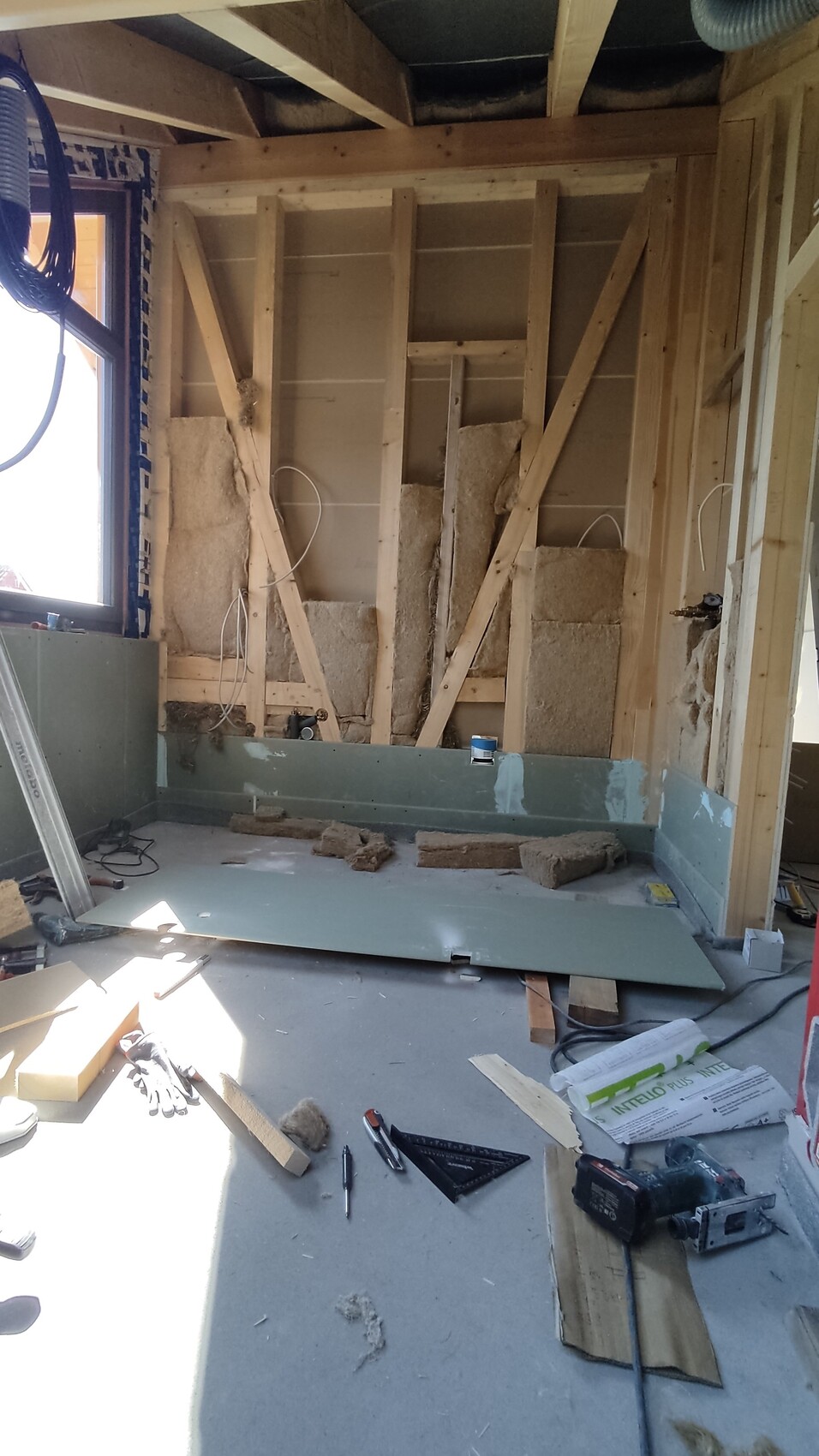 Unfertiges Badezimmer während Renovierung: freigelegte Holzwände, Dämmung und Werkzeuge.
