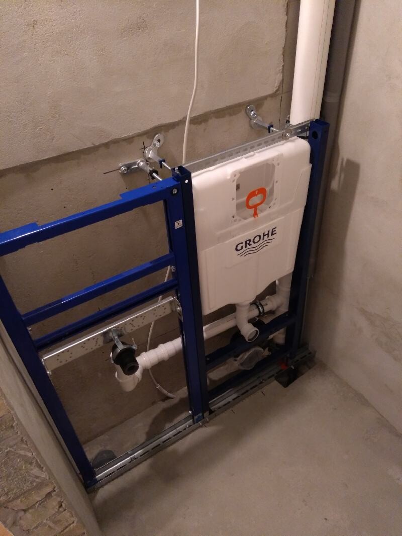 GROHE Spülkasten in blauem Rahmen, Rohbau-WC mit sichtbaren Rohren.
