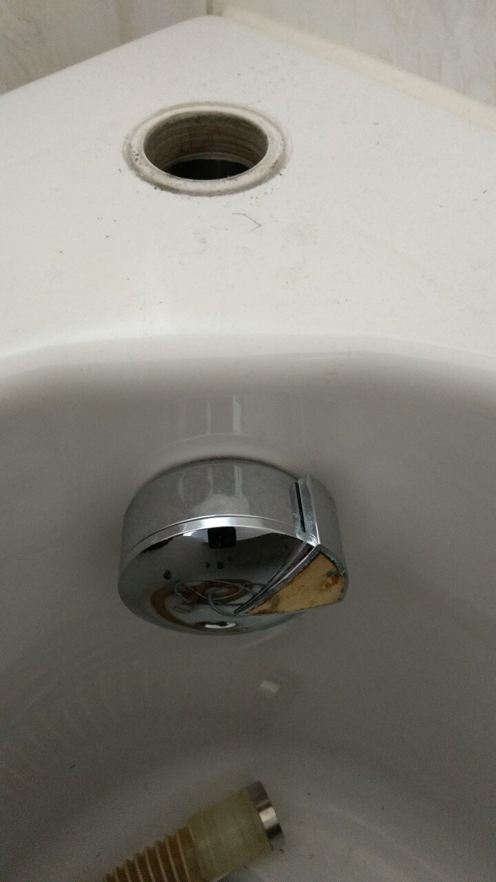 Innenansicht eines Toilettenspülkastens mit chromer Armatur und Anschlussrohr.