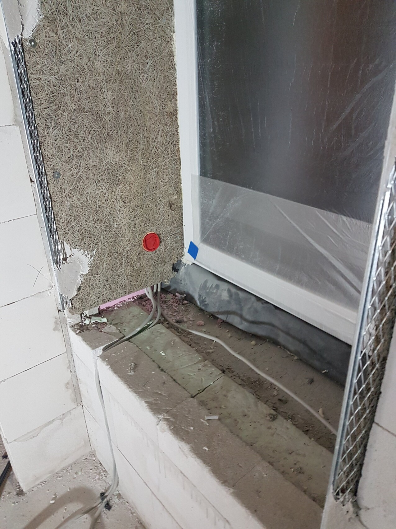 Rohbau-Badezimmer mit Dämmung, Wasserleitungen und Glasfront mit Schutzfolie