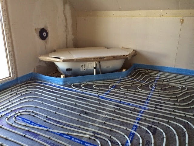 Rohbau-Badezimmer mit verlegten Fußbodenheizungsrohren und Badewanne an der Rückwand.
