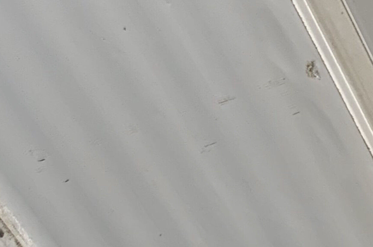 Grau glänzende Metalloberfläche mit Kratzern; rechts silberne Kante.