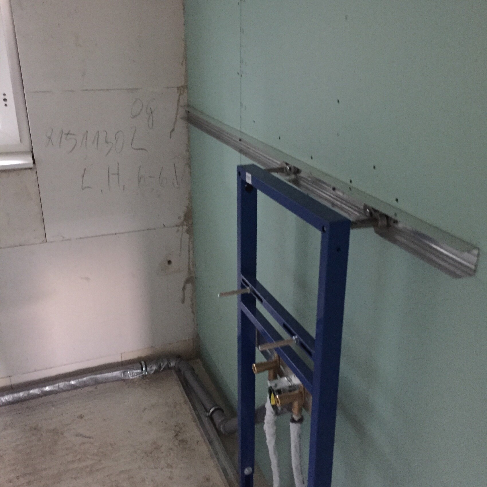 Badezimmer-Rohbau mit Toilettenrahmen, Rohren und grüner Wand