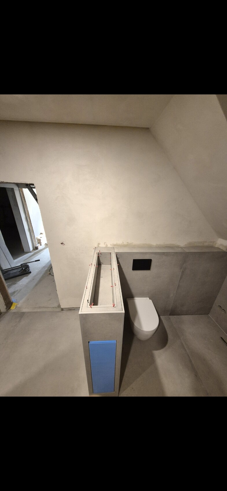 Badezimmer im Rohbau mit Toilette und unfertigen Sanitärinstallationen