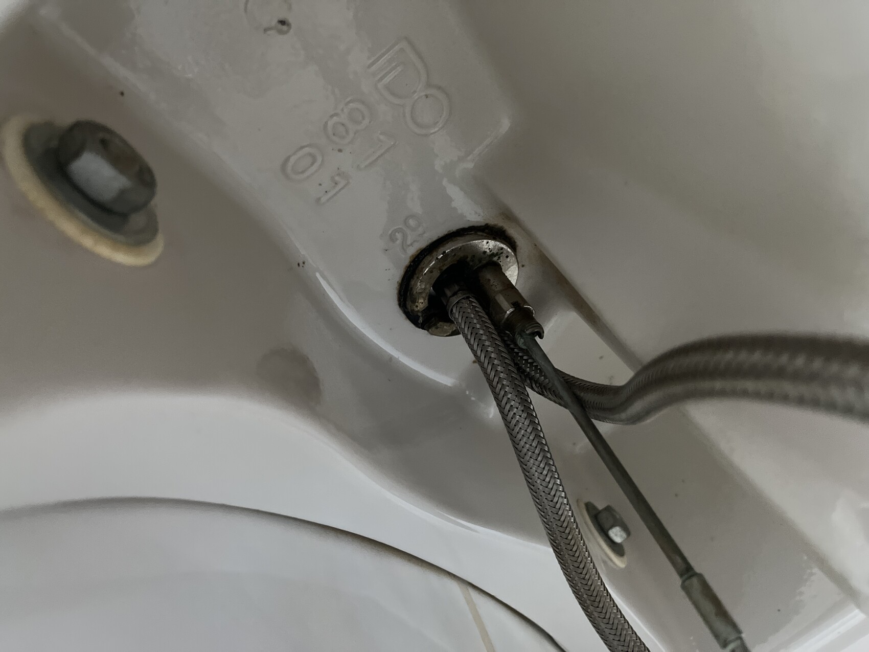 Unterseite eines Spülbeckens mit flexiblen Edelstahlleitungen und Anschlussstücken