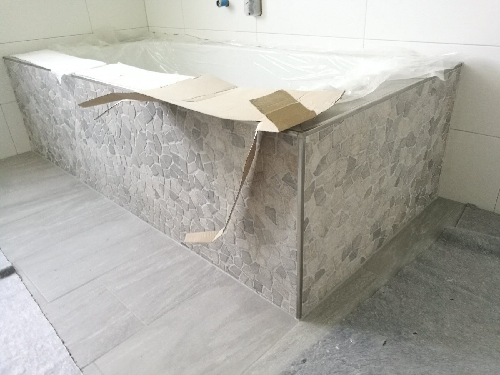 Badewanne mit Mosaikverkleidung im Badezimmer unter Bauarbeiten