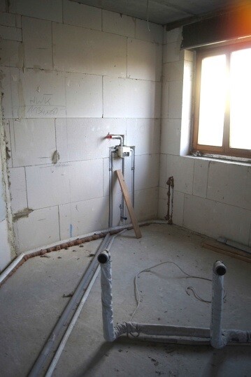 Rohbau eines Badezimmers mit Installationsrohren und Fenster