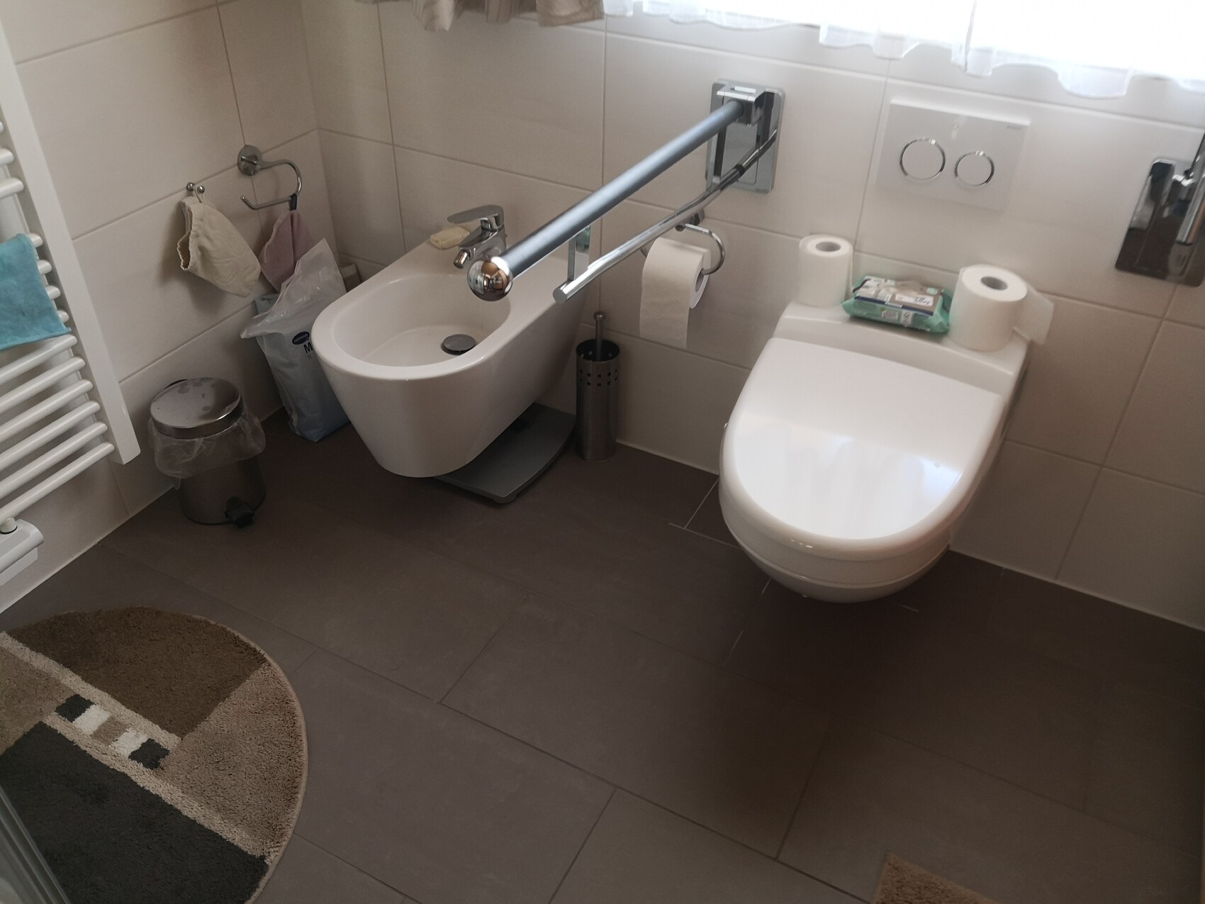 Helles Bad mit Bidet links und wandhängendem WC rechts, zwei Toilettenrollen sichtbar.