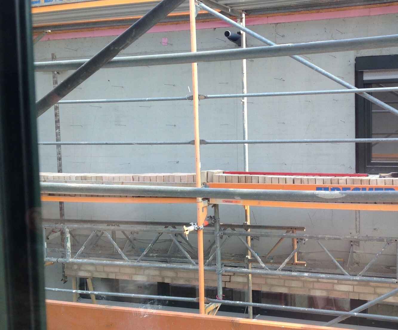 Außenbaustelle mit Gerüst und Baustrukturen vor einer Fassade