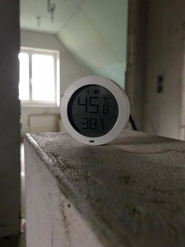 Runder Digitalhygrometer auf staubigem Fensterbrett in leerem Raum; 45,8 °C und 38,3 % RH