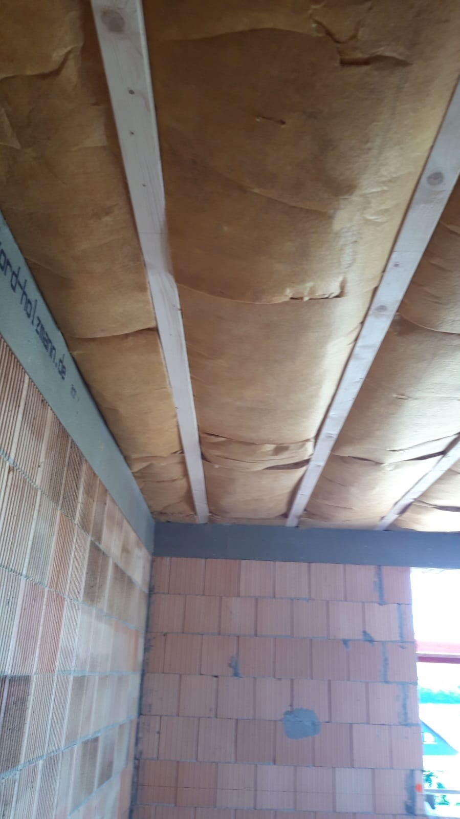 Unverkleidete Decke mit Dämmung aus Mineralwolle zwischen Sparren in Bauphase