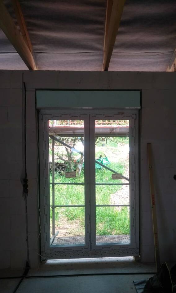 Doppeltes Glasfenster-Türenrahmen im Bau, Blick nach grünem Garten, Gerüst außen