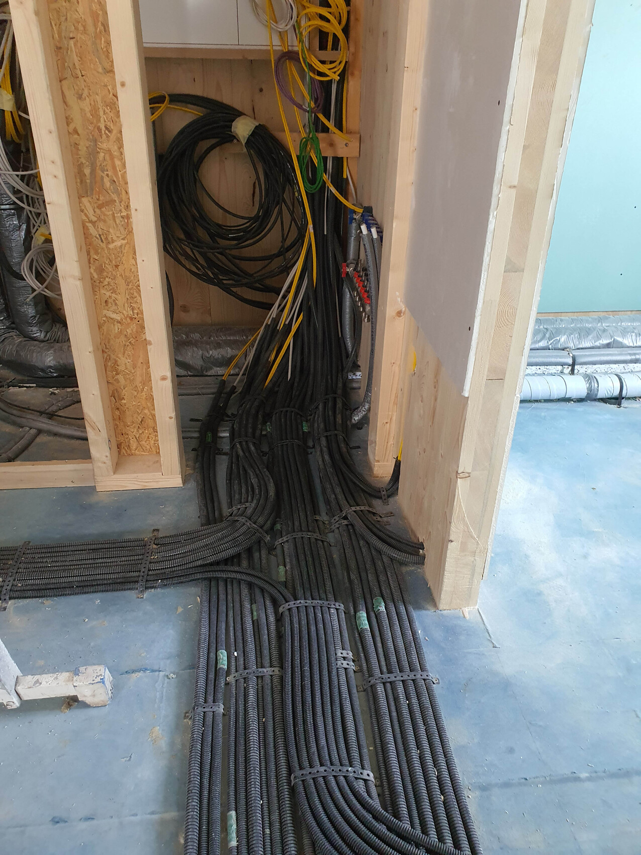 Baustelle mit vielen schwarzen Kabelbündeln auf dem Boden und in der Wandkonstruktion.
