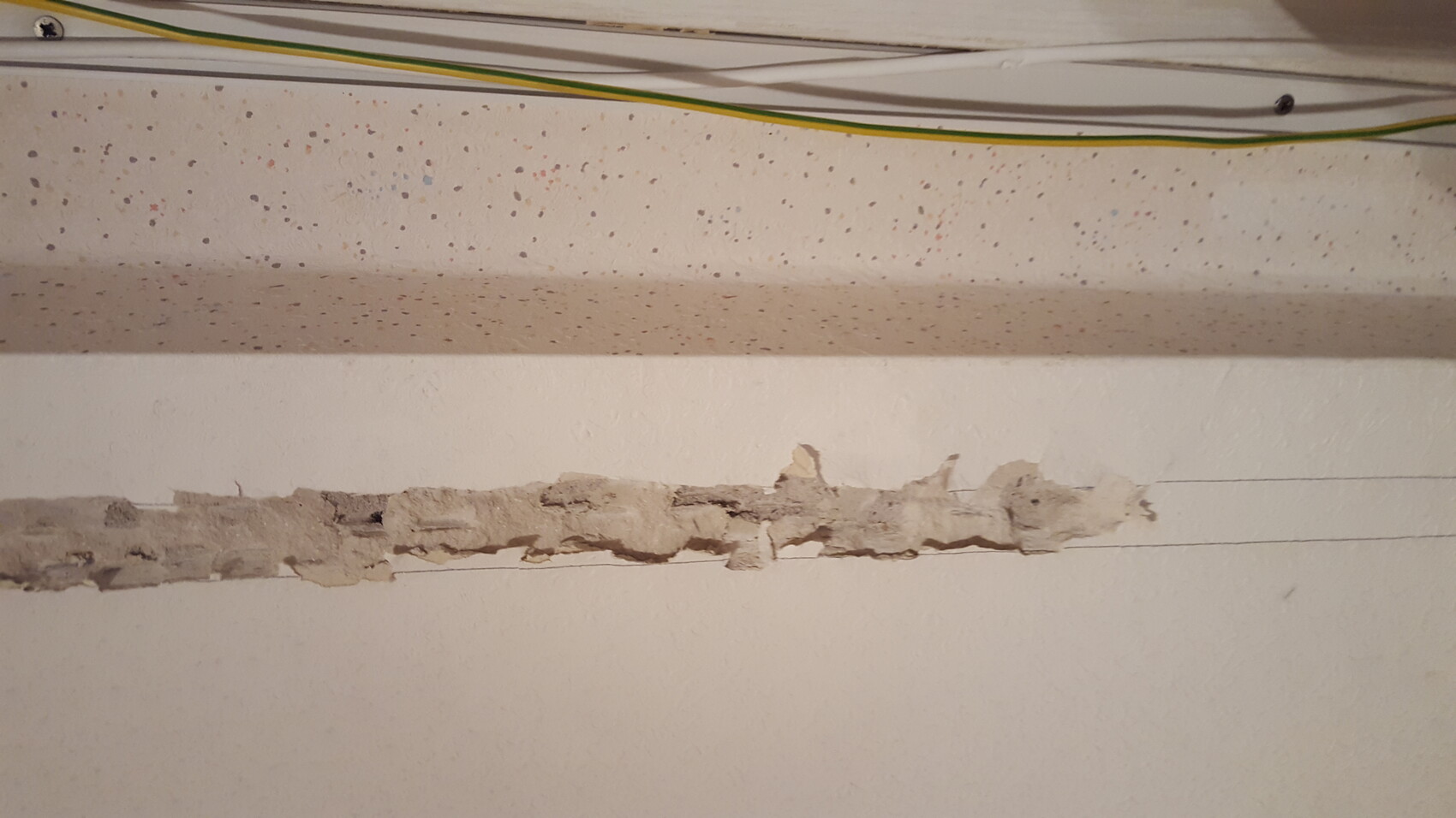 Freigelegtes Mauerwerk in Innenwand, Risse und sichtbare Kabel