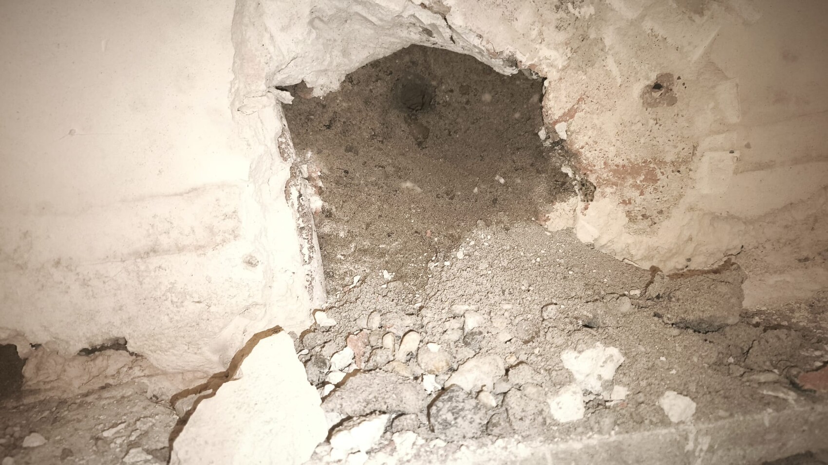 Kellerwand mit Loch im Putz und Schutt aus Betonbruch