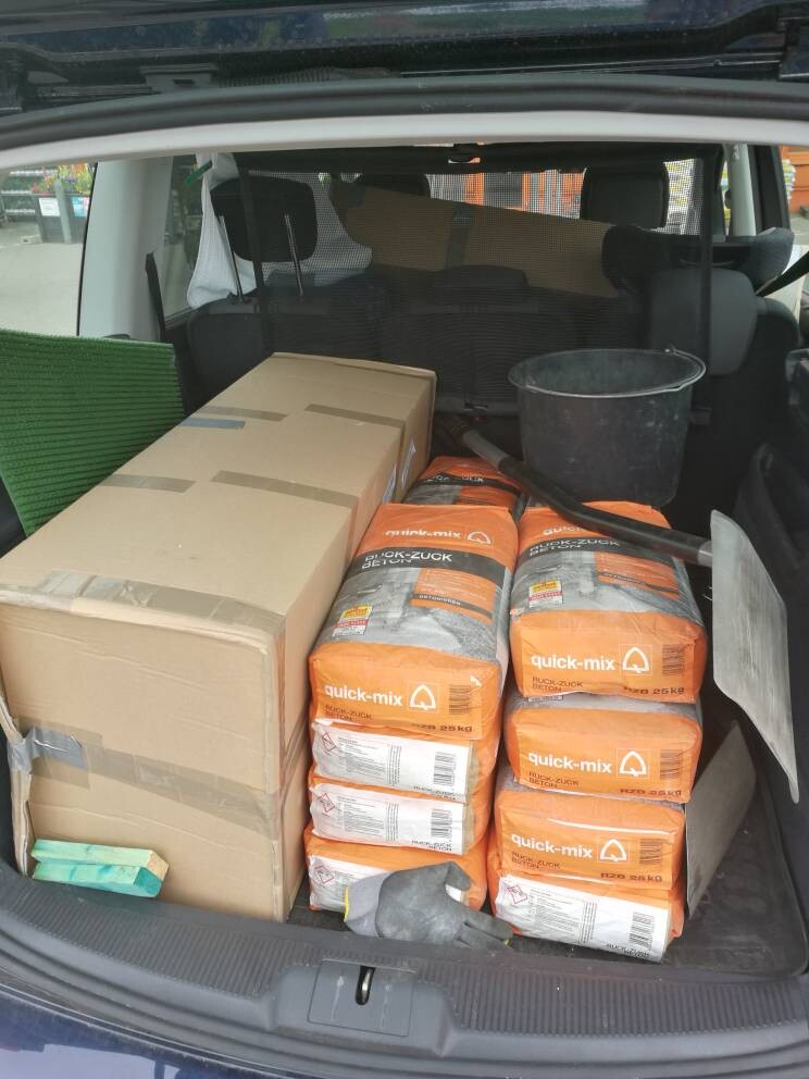 Kofferraum eines Autos voll beladen mit Kartons, Beton-Säcken und Eimer.