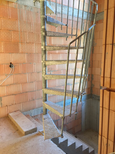 Provisorische Metalltreppe in einem Rohbau mit Ziegelwänden