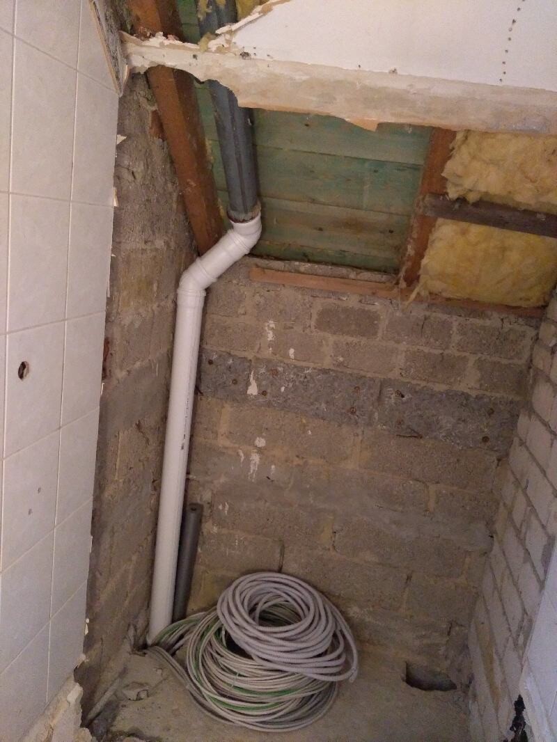 Kellerraum: PVC-Rohrleitung mit Biegung, lose Kabelrolle auf Betonboden.