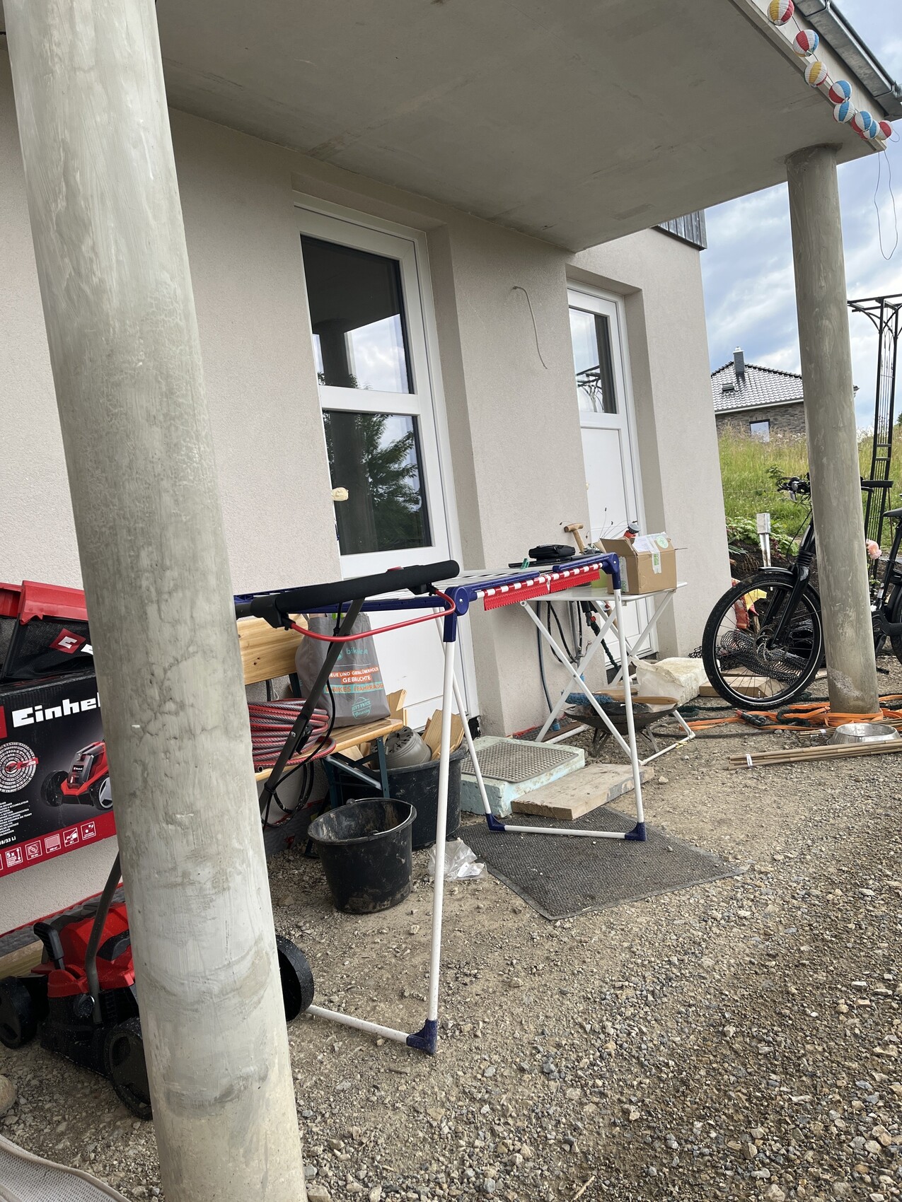 Außenansicht einer Baustelle am Haus mit Tür, Fenstern und Baumaterialien.