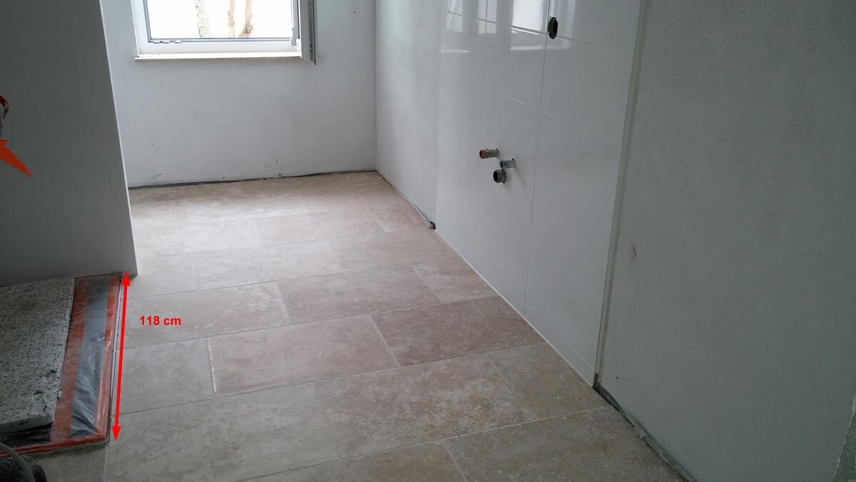 Badezimmer im Bau mit Fliesenboden, Wandfliesen und offenen Sanitäranschlüssen.