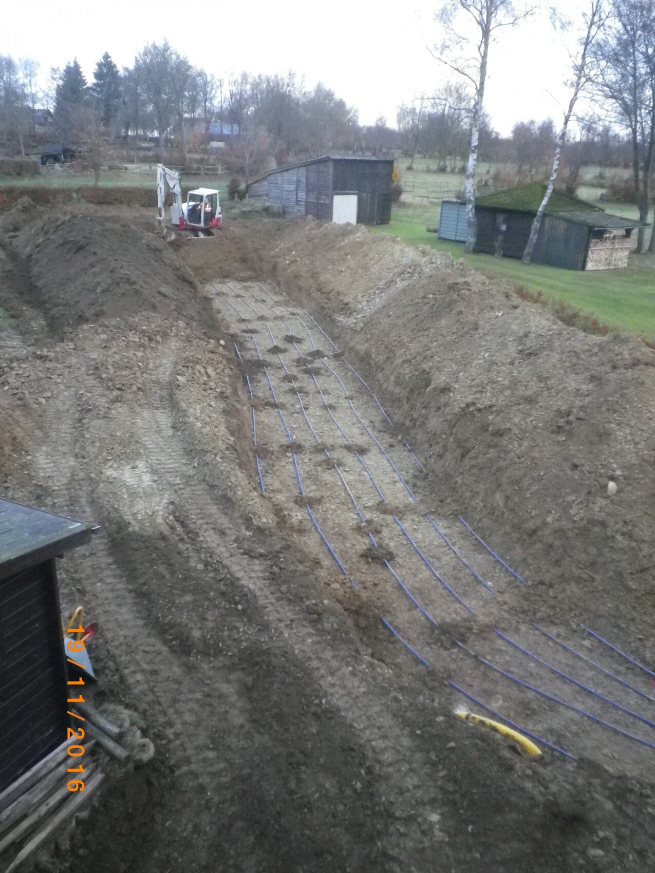 Baugraben mit verlegten Rohrleitungen fuer Fussbodenheizung auf Baustelle