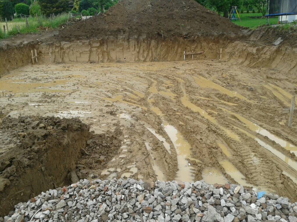 Baugrube mit Schlamm, Erdarbeiten und Fundamentvorbereitung im Baugelände
