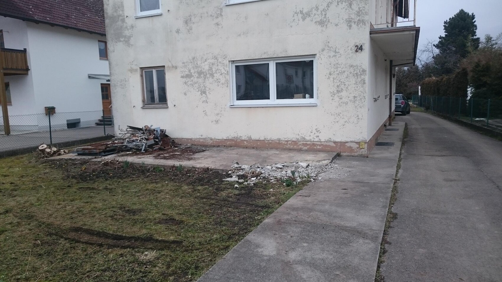 Aussenwand eines Mehrfamilienhauses mit abgeblattertem Putz und Bauschutt davor.