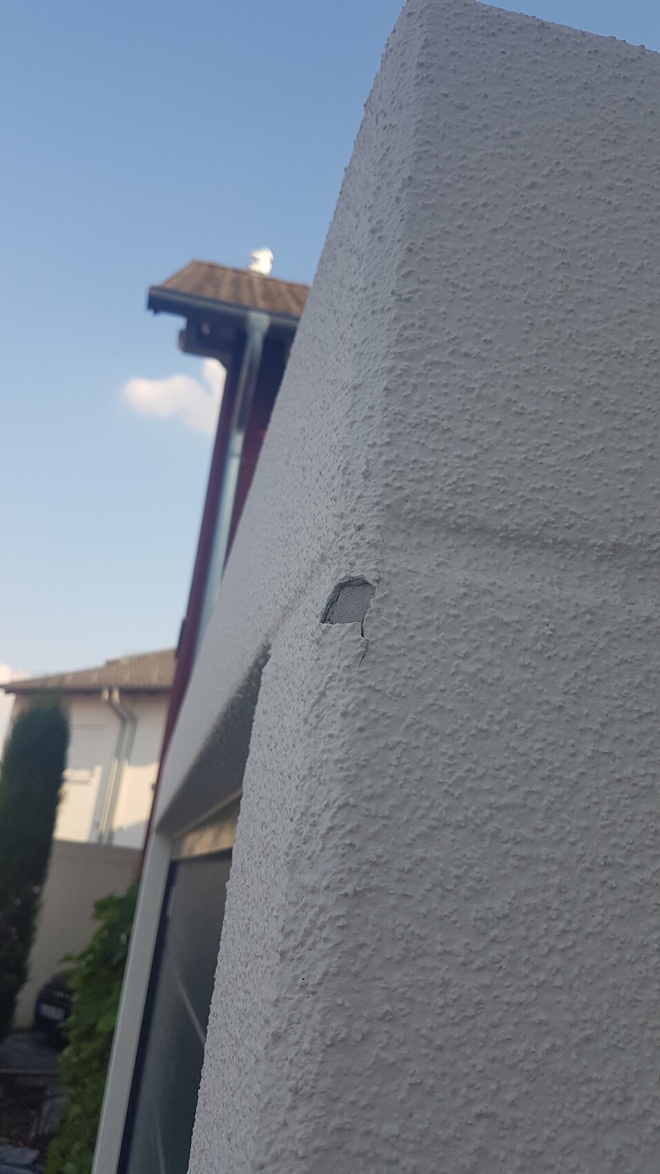 Außenwand mit Putzschaden und kleinem Loch in der Fassade