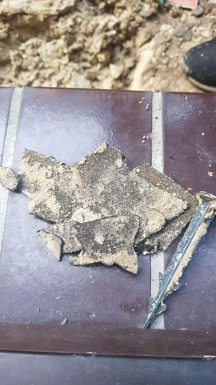 Bröckelnde Fliesenreste mit Sand auf Baustelle