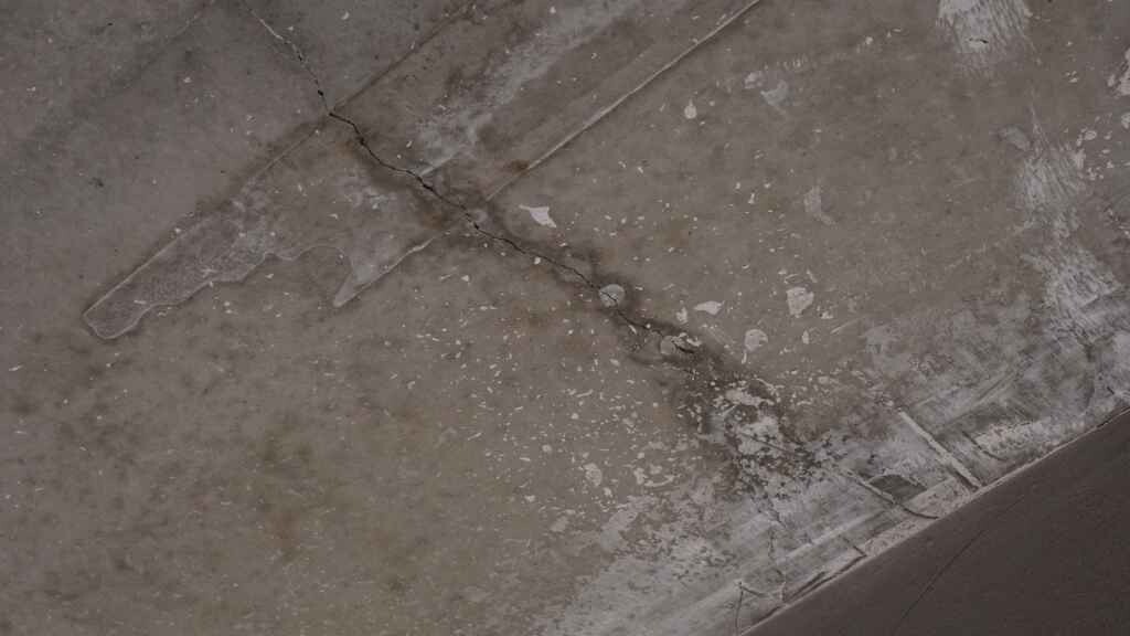 Rissiger Betonboden mit Flecken und Feuchtigkeit