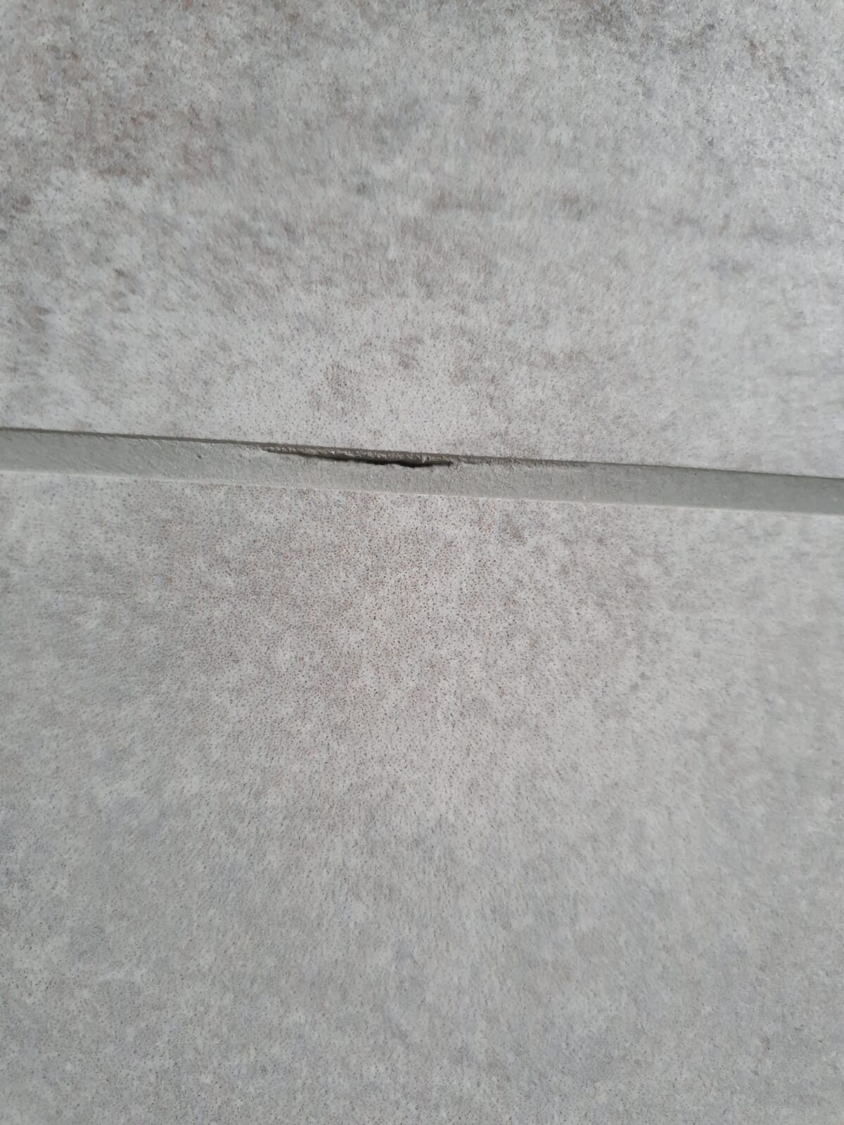 Graue Betonoberfläche mit einer feinen horizontalen Risslinie.