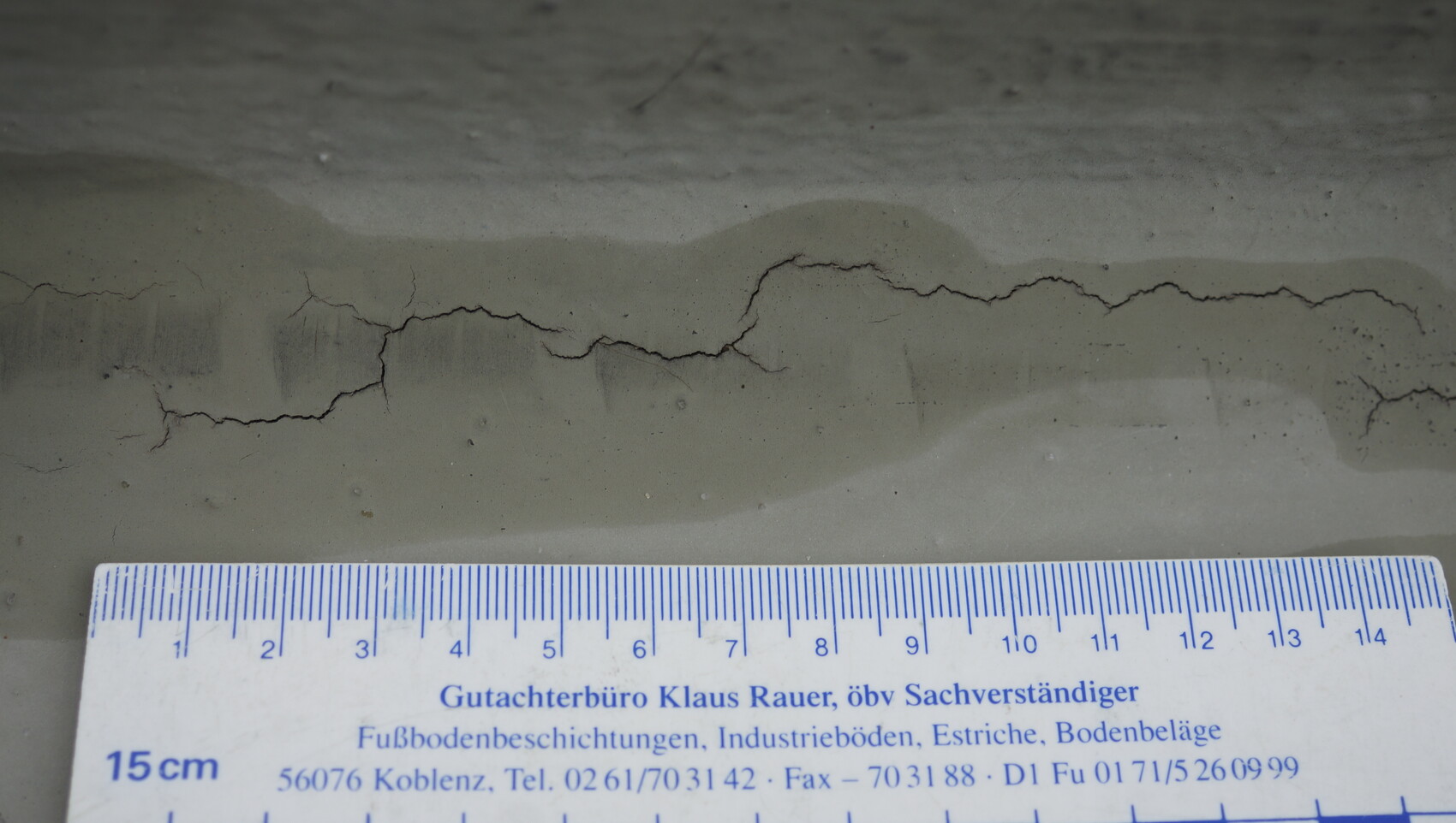Betonboden mit Rissen und Maßband zur Baumangel-Dokumentation