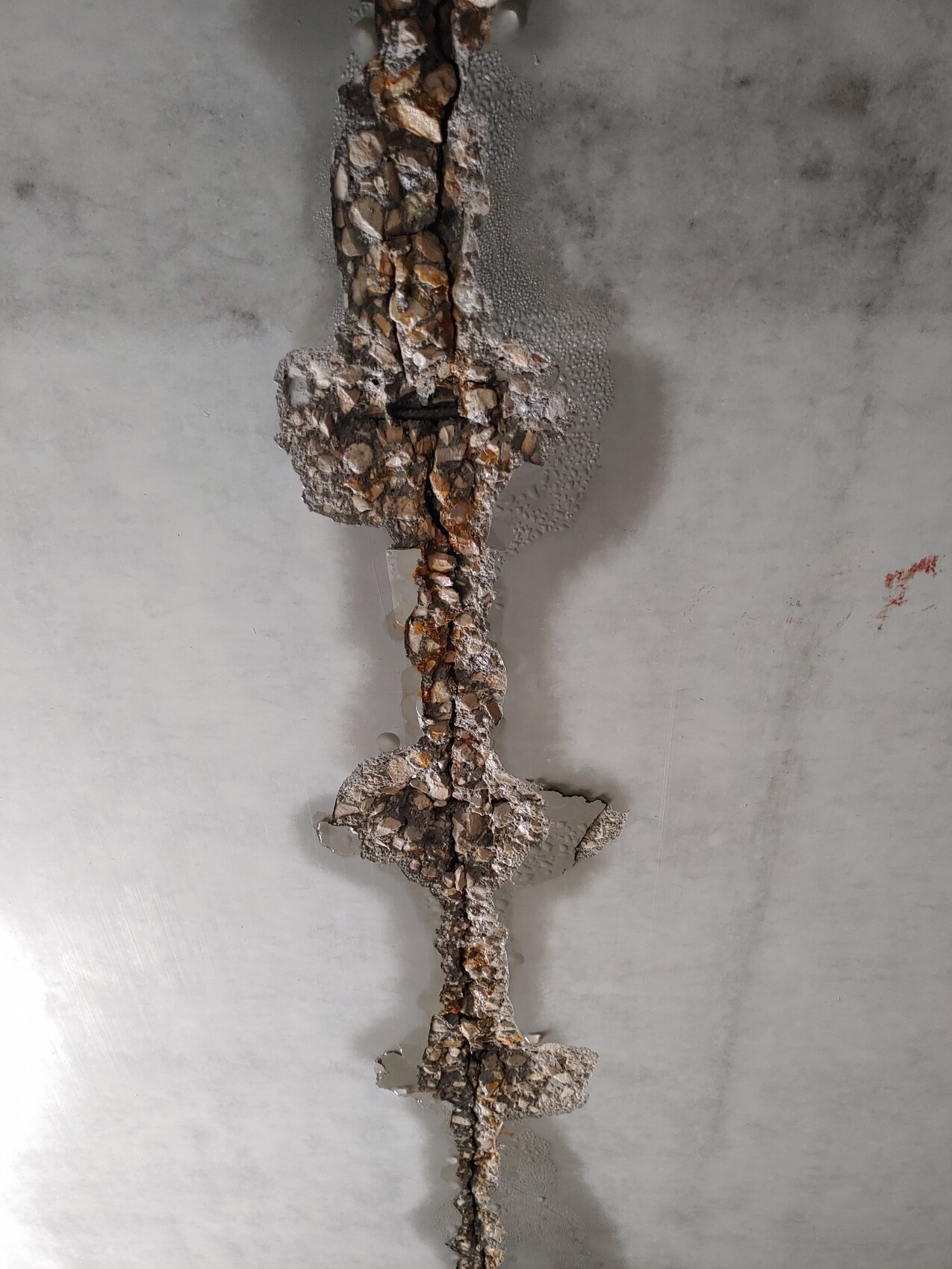 Vertikale Betonfuge mit Kies und Zement in grauem, rauem Beton.