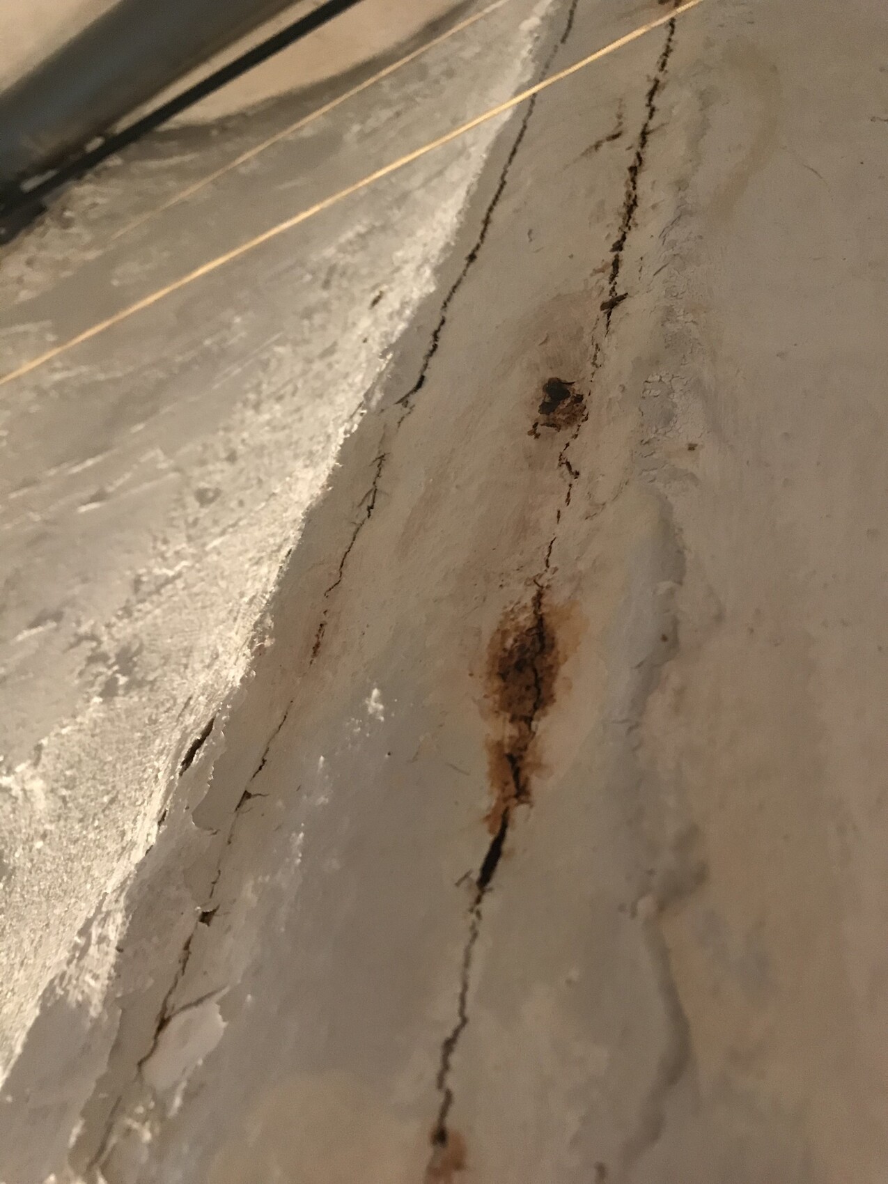Rissiger Betonboden mit rostigen Flecken und Abplatzungen.