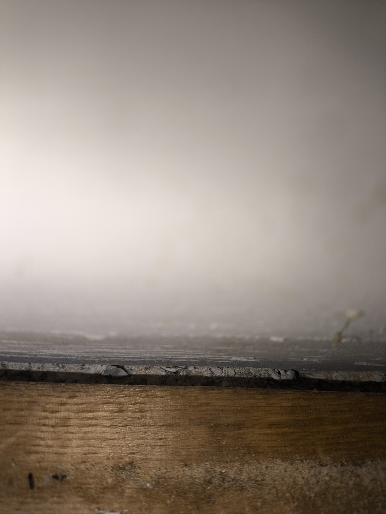 Nahaufnahme einer Bodenkante mit Holzunterlage und Betonboden, sichtbarer Spalt