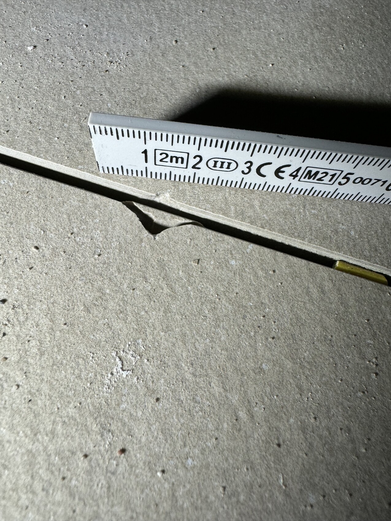 Nahaufnahme eines Messbands auf Betonboden mit einem Riss im Material.