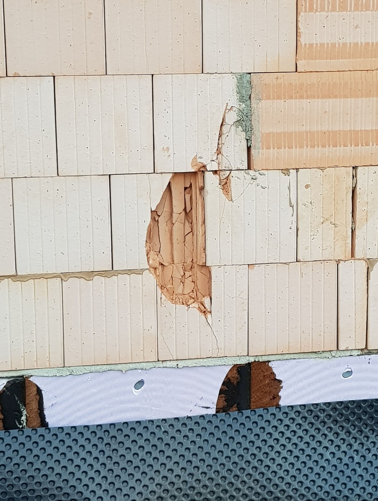 Ziegelwand mit Loch und beschädigter Oberfläche, Baumangel erkennbar