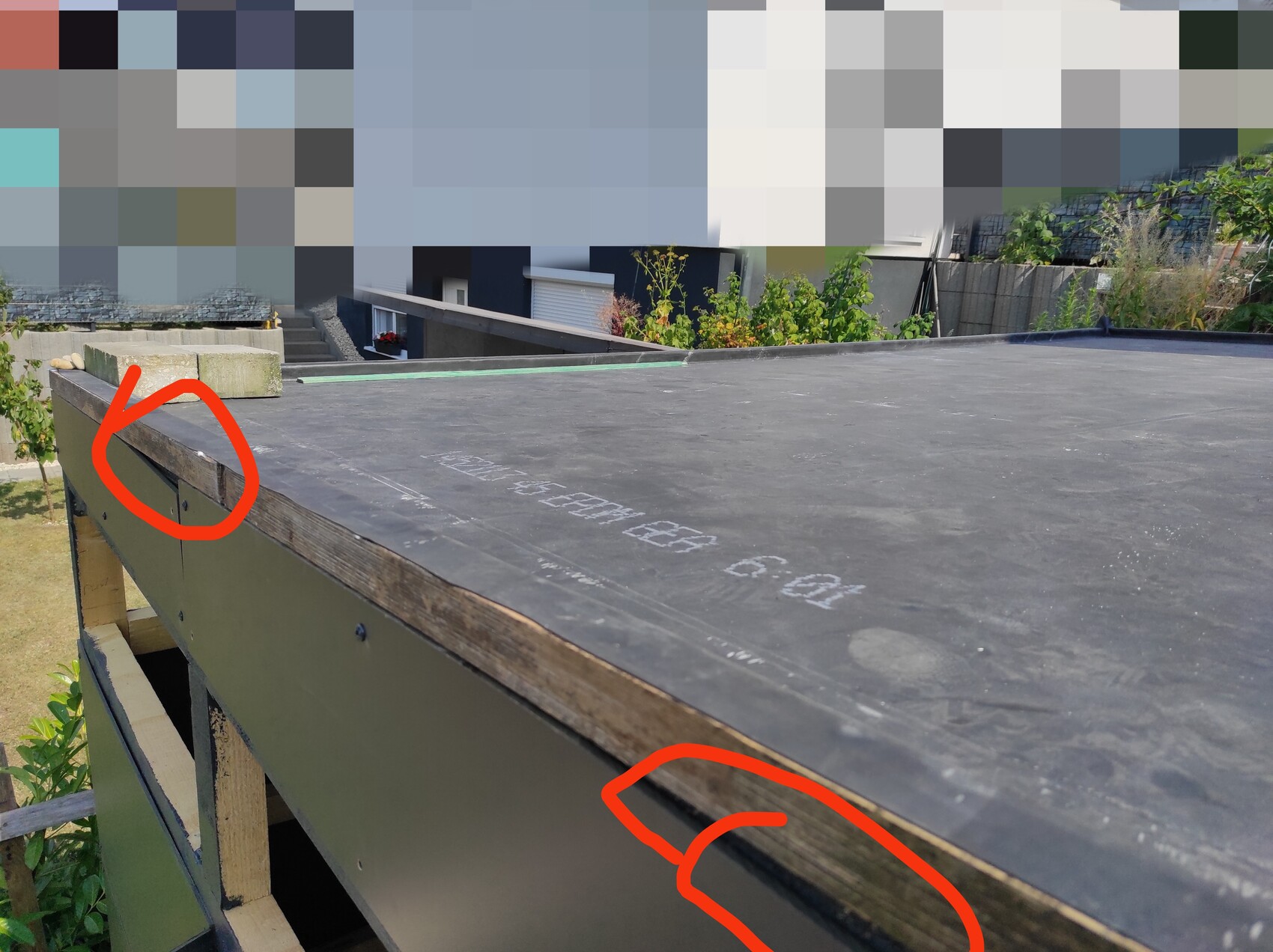 Flachdach-Terrasse mit schwarzem Belag; zwei rote Kreise markieren Randspalten am Holzrand.