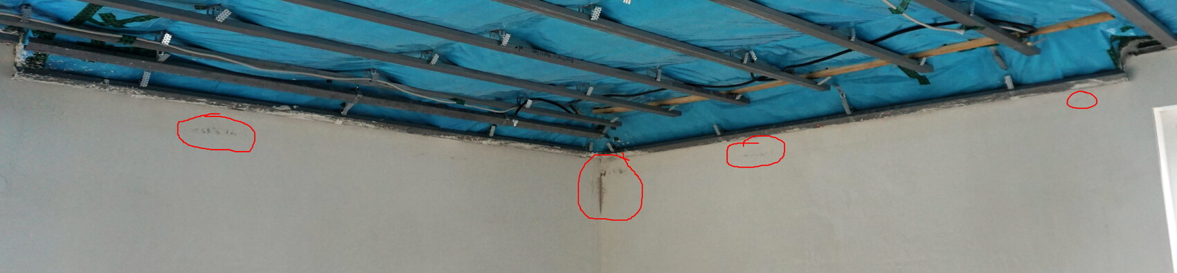Innenraum mit blauer Abdeckplane an der Decke; Wandrisse durch rote Kreise markiert.