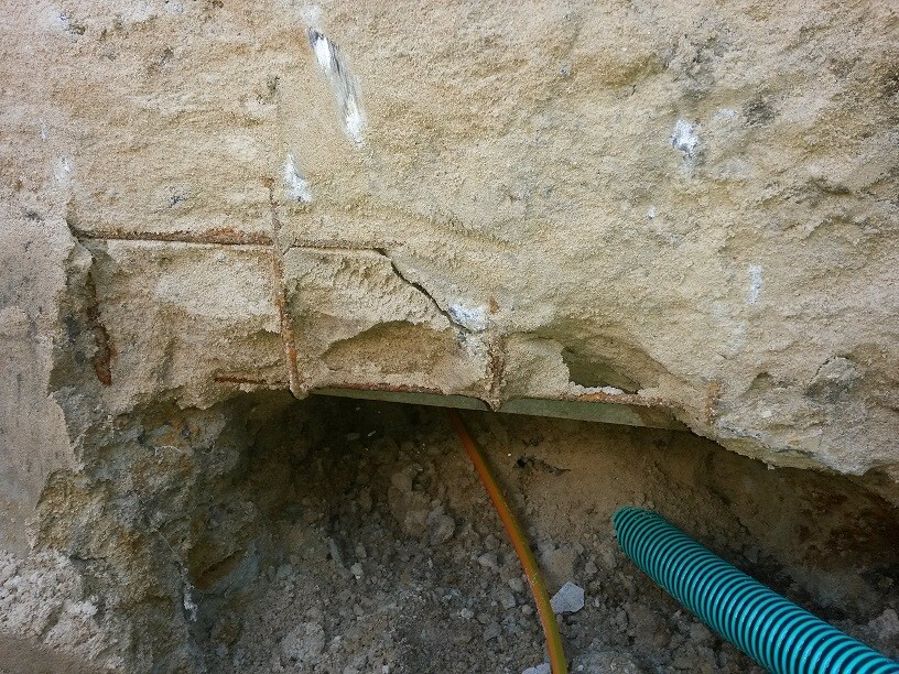 Bruchstelle im Betonfundament mit freiliegten Kabelrohren auf Baustelle