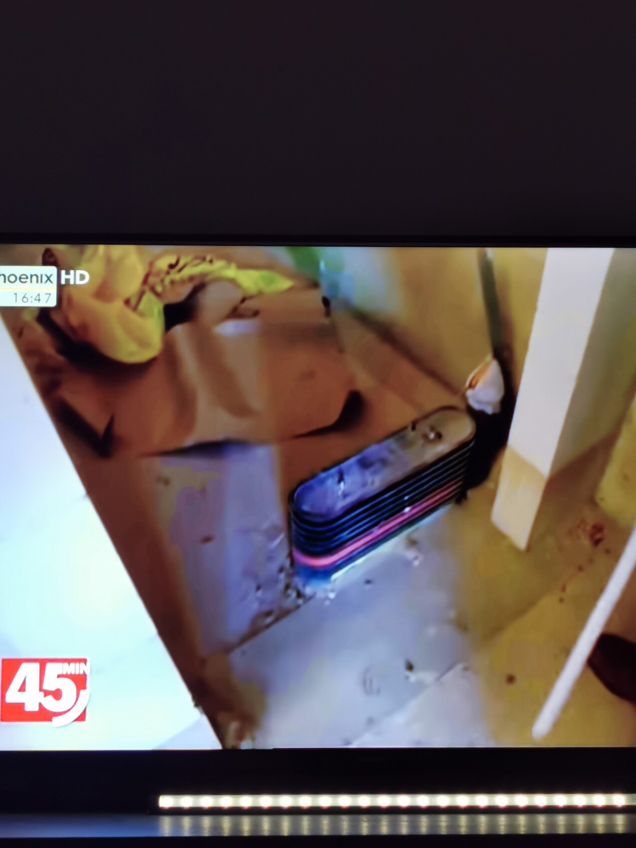 Unscharfes TV-Bild: Gelb gestrichene Wand, bunter gestreifter Koffer liegt auf dem Boden.