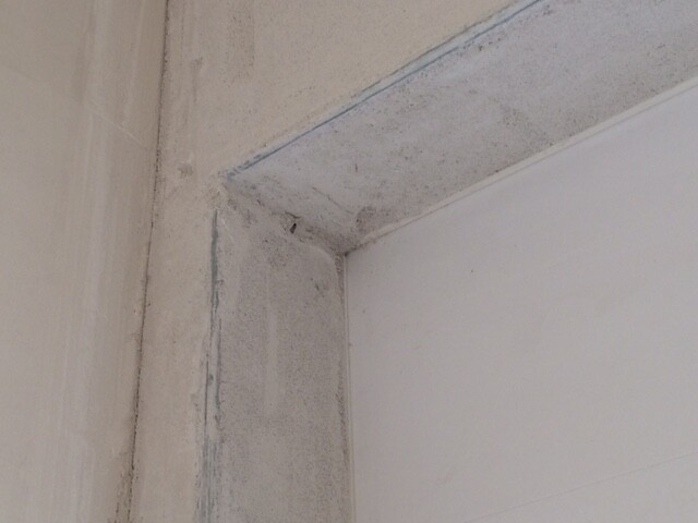 Detail einer Innenwand-Ecke mit unregelmäßig verputzter Fläche im Rohbau