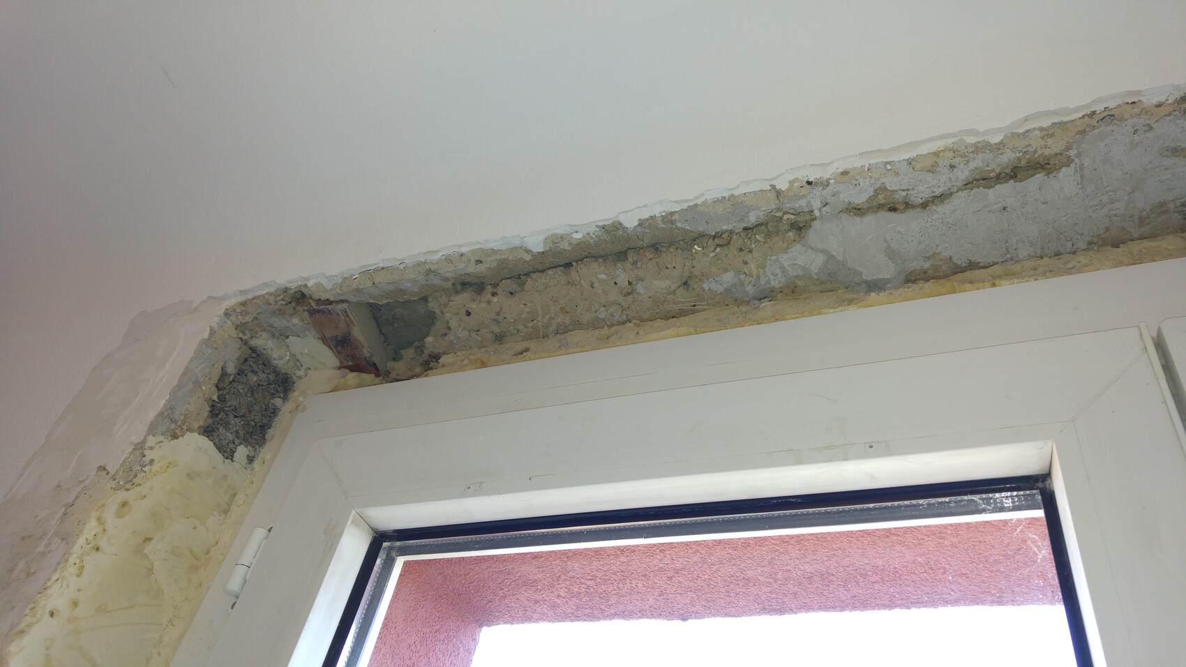 Beschädigte Innenwand um Fenster mit abgeplatztem Putz und Feuchtigkeit