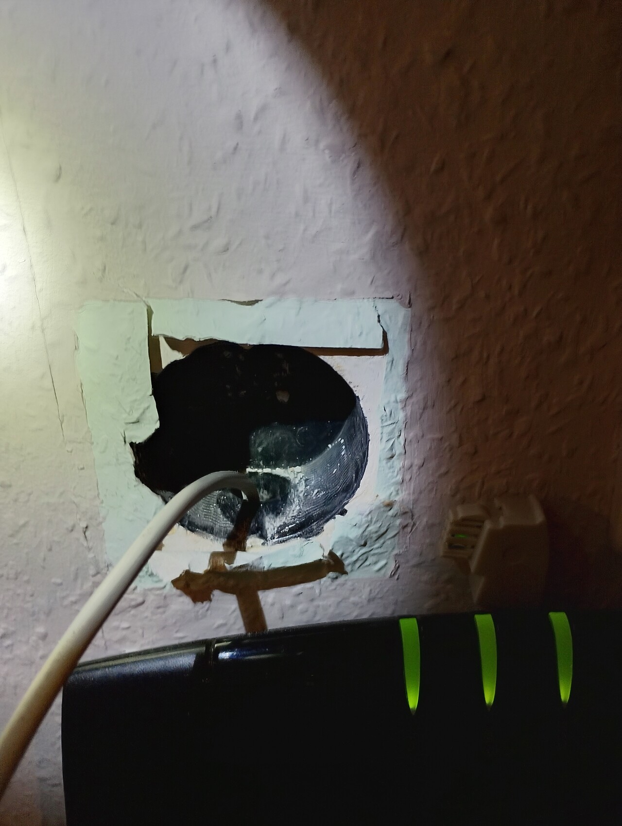 Loch in Innenwand mit Rohr und Kabel, Putz bricht um das Loch