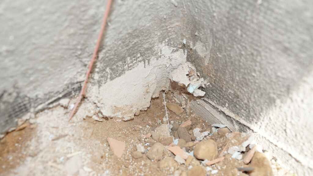 Eckenputz bricht von der Innenwand, Schutt und Putzreste am Boden