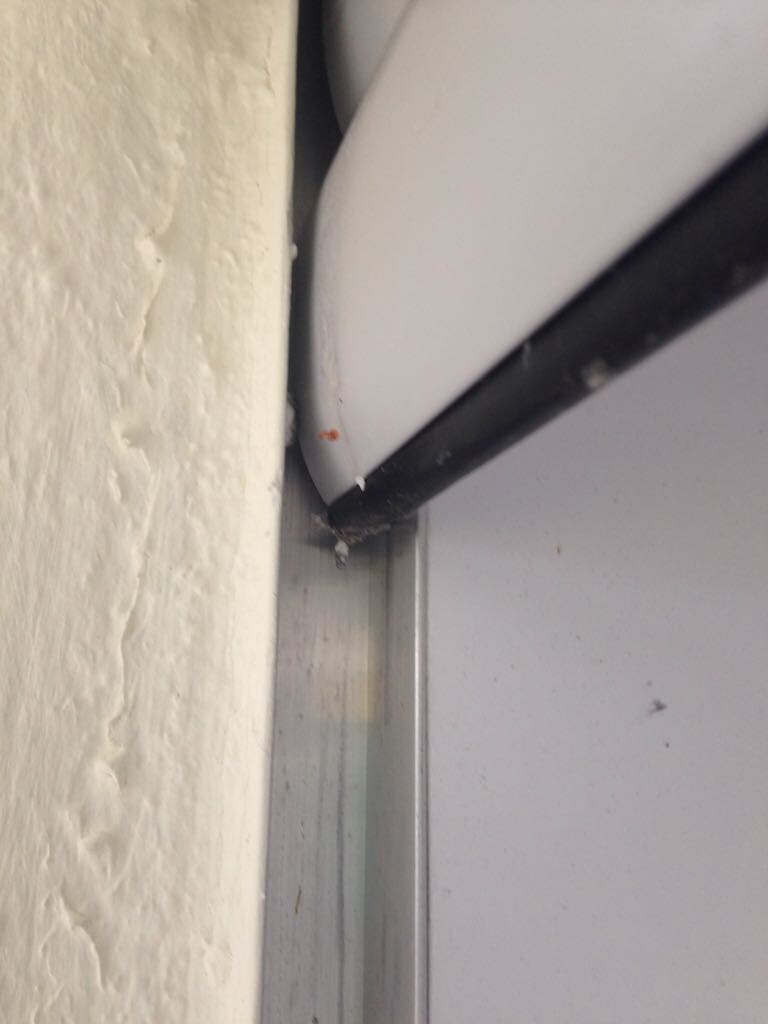 Nahaufnahme eines Türrahmens mit schwarzem Kabel an der Wand, Staub und Beschädigungen sichtbar.