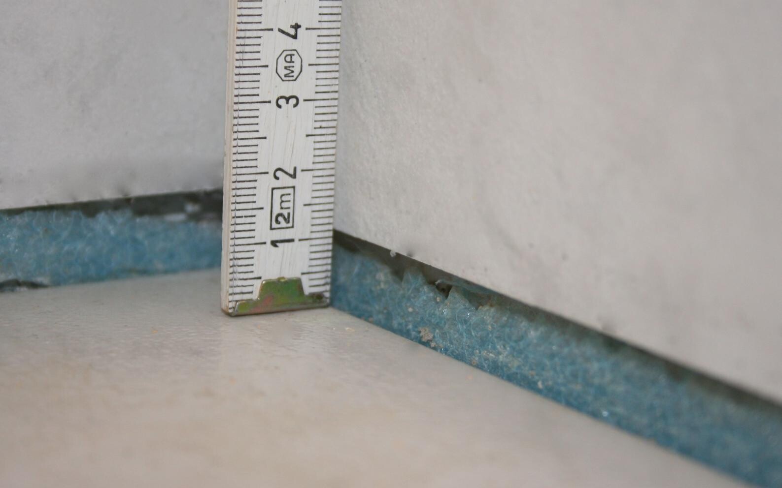 Messlatte neben Spalt zwischen Bodenplatte und Wand, Baufehler sichtbar
