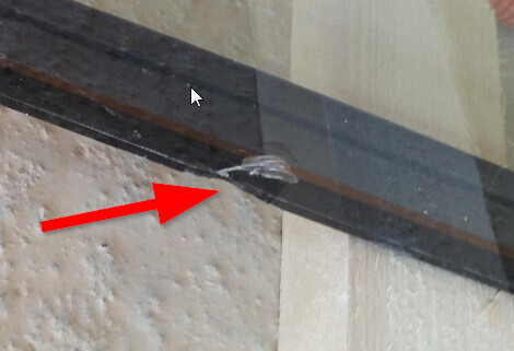 Kleiner Riss im Wandbauteil neben einer dunklen Leiste sichtbar