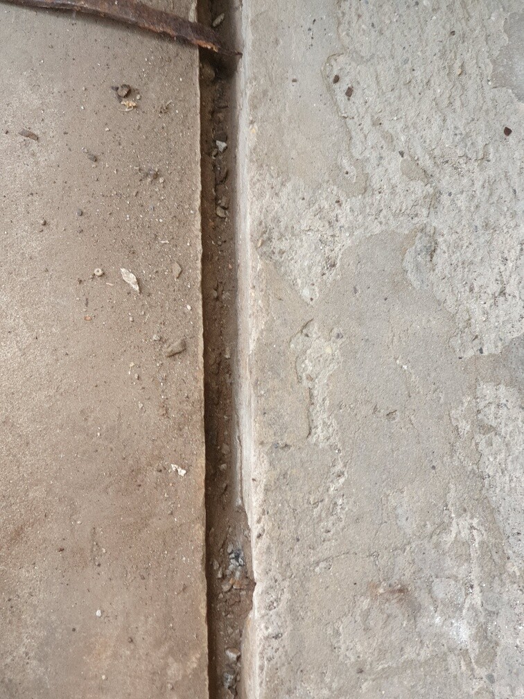 Schmale Spalte zwischen zwei rauen Stein- oder Betonflächen mit Staubkörnern.