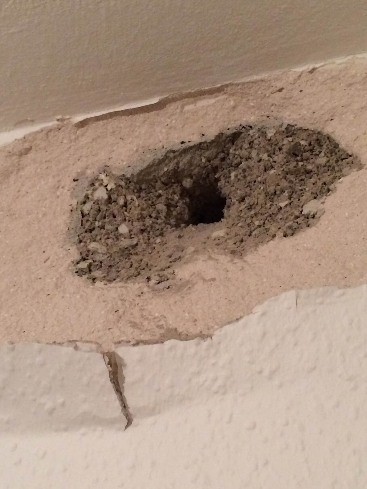 Loch im Wandputz mit grobem Mörtel und Bruchkanten – Hinweis auf Baumangel in der Wand
